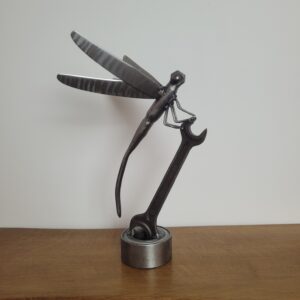 sculpture de libellule en métal recyclé posée sur clé plate